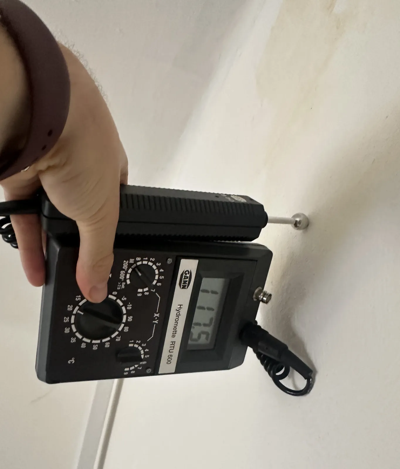 Měření vlhkosti na stěně pod stropem se skvrnami od vody.